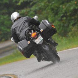 yağmurda motosiklet sürüşü, ıslak asfaltta sola dönen yatık motosiklet